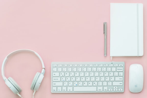 Apple compact keyboard magic mouse and corded headphones on pink surface